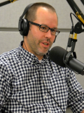 Photograph of man speaking into a microphone in a studio