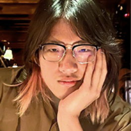 Photograph of personal with chin-length hair, glasses and hand on their face