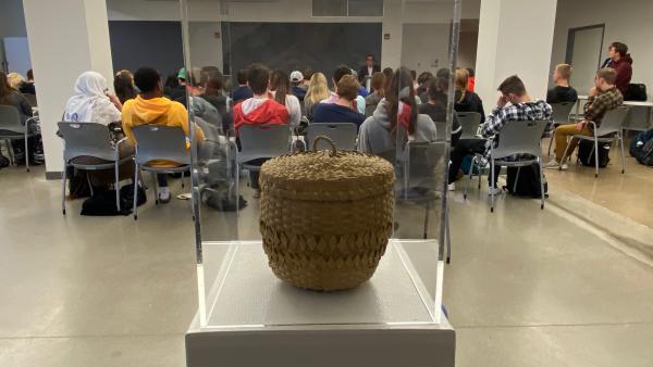 Photograph of Potawatami basket display and audience listening to Professor Daniel Rivers
