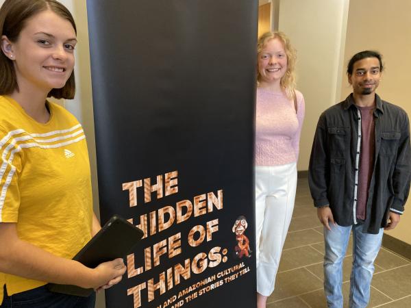Photograph of student curators along the title banner of "The Hidden Life of Things" exhibit