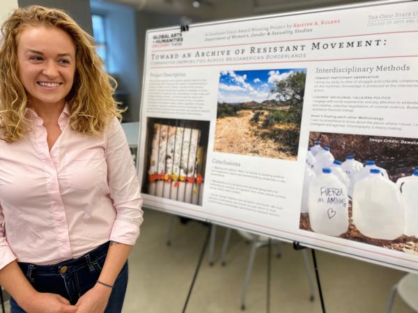 Photograph of graduate student in front of their research poster