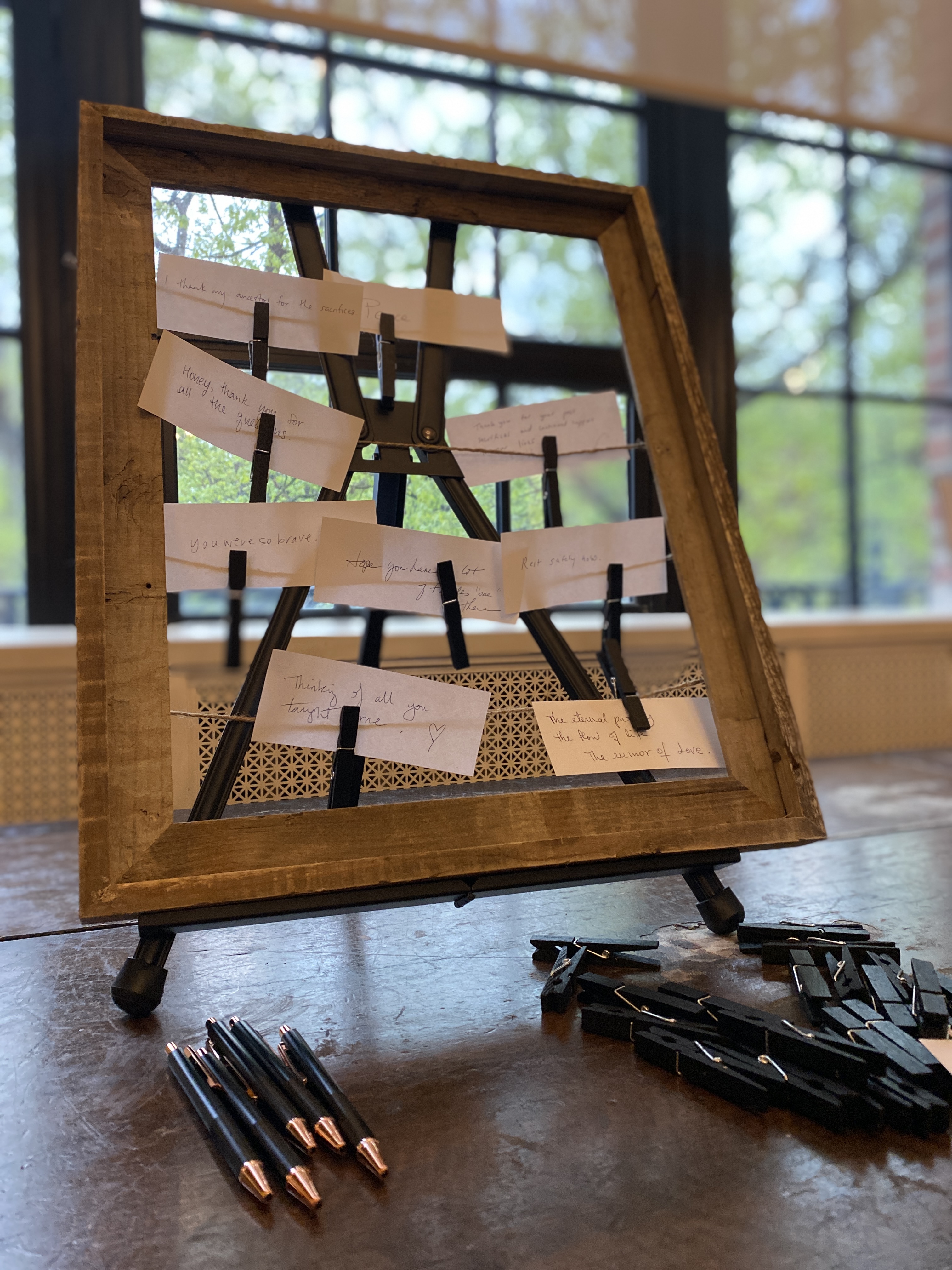 Wood frame with notes pinned to it using black clothes pins