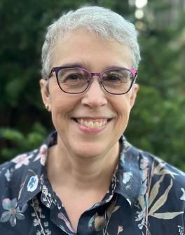 Woman in glasses and floral shirt smiling at camera