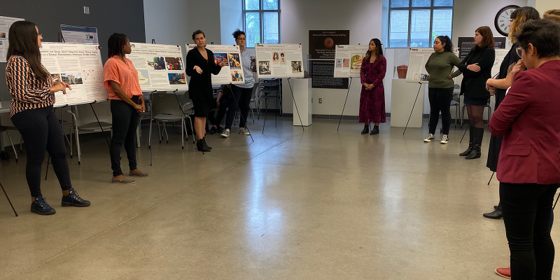 Graduate students standing in half circle around research posters