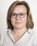 Photograph of woman with short blonde hair, white glasses and a white button-up shirt