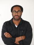 Man with arms crossed wearing glasses and a dark shirt