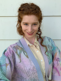 Smiling woman with long red hair wearing yellow shirt and colorful kimono