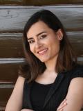 Smiling woman with dark hair standing in front of wood backdrop