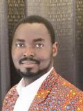 Black man with short hair and a goatee wearing a brightly-colored suit jacket and white shirt