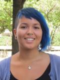 Smiling person with blue hair standing outdoors