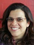 Smiling woman with long dark hair and glasses in from tof red wall