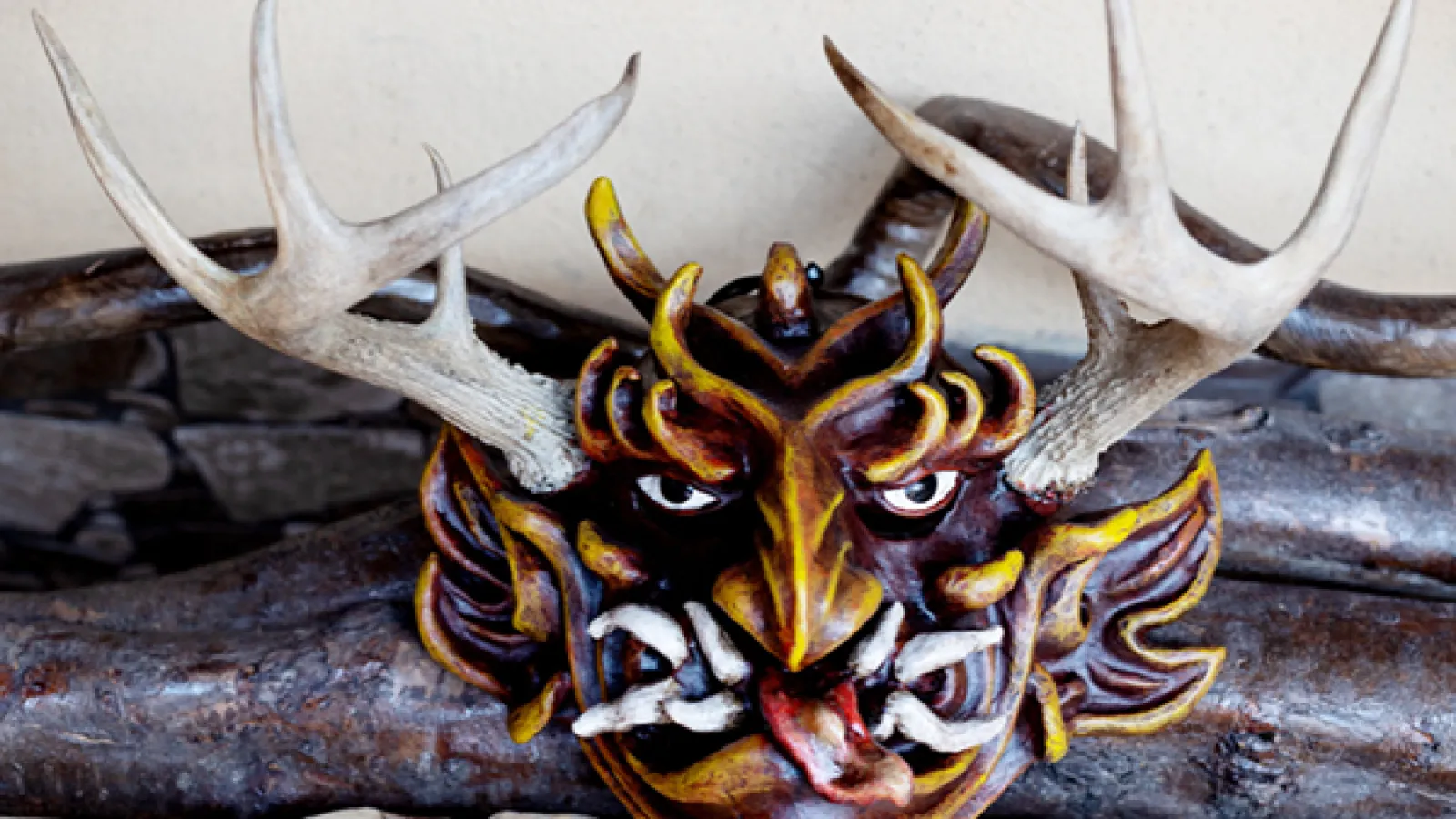 Carving of a masked face with antlers