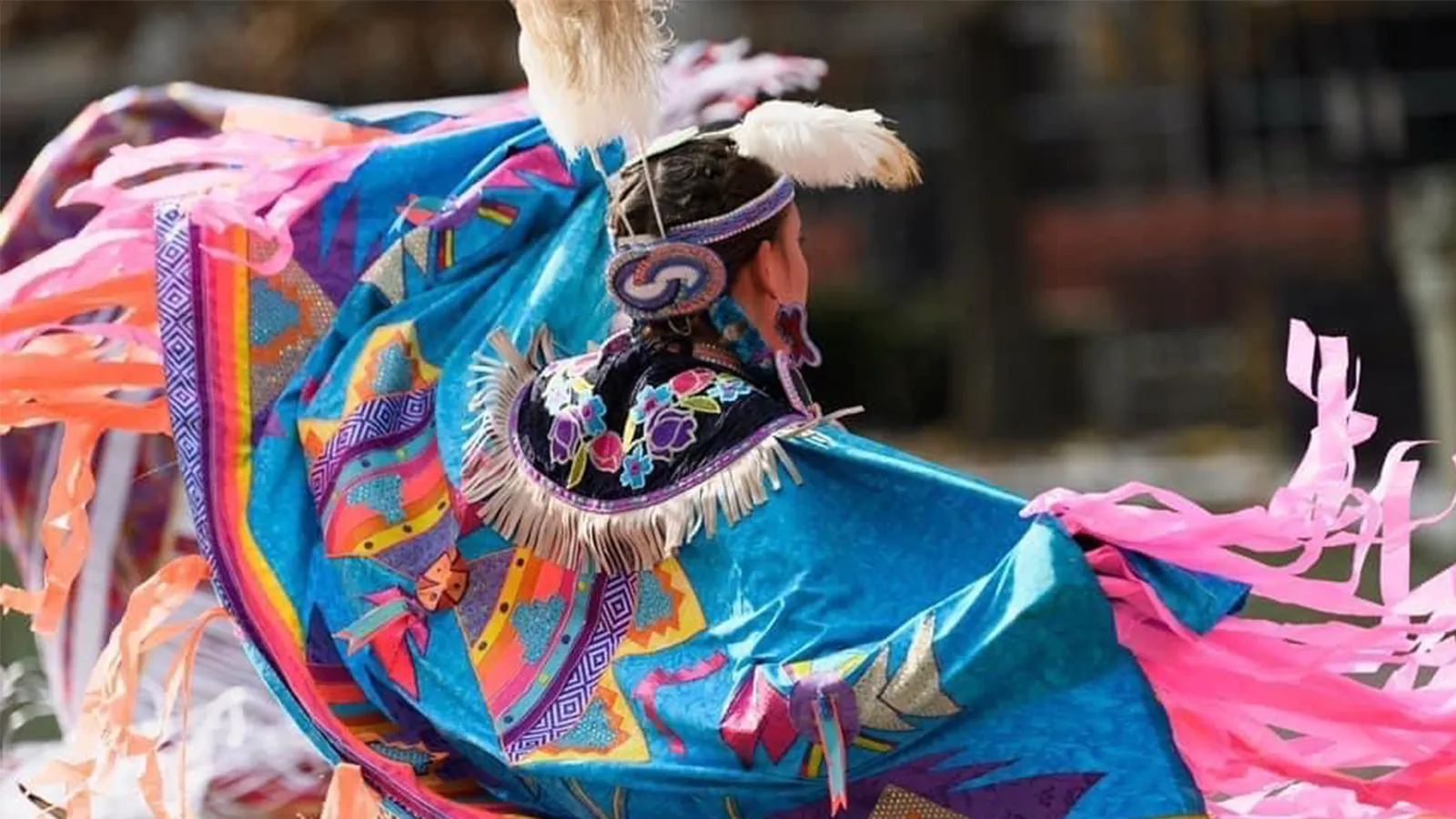 Person with a bright shawl dances at a Pow Wow