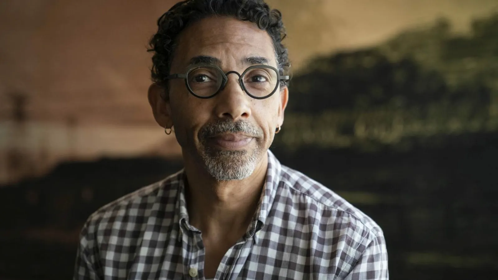 Man with short dark hair and glasses wearing a checkered shirt