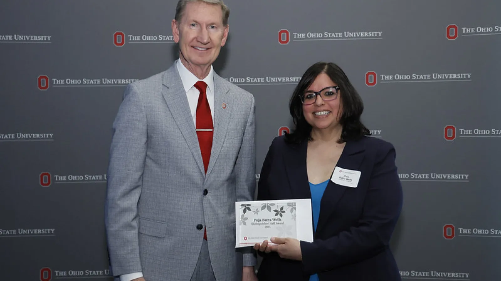 Two people posing with framed award