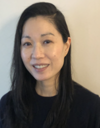Smiling woman with long dark hair in front of white wall