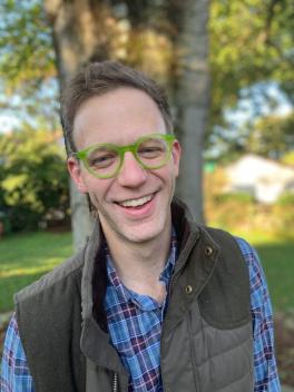 Smiling man with glasses and a vest