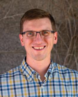 a smiling man wearing a plaid shirt and glasses