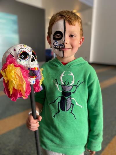 A child with half their face painted holding a procession baton