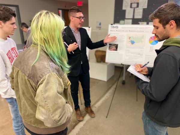 Photograph of graduate student in front of their research poster