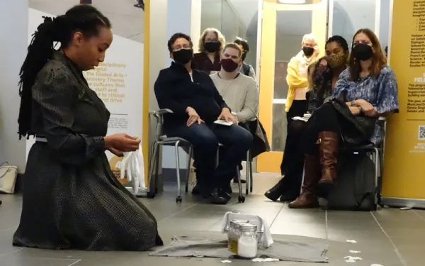 Dancer kneels at altar, mid-performance