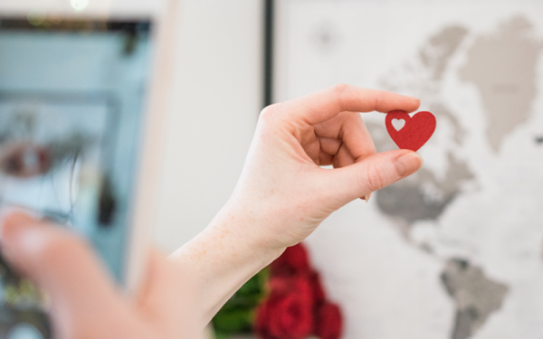 Photograph of hand holding red heart with heart cutout within it