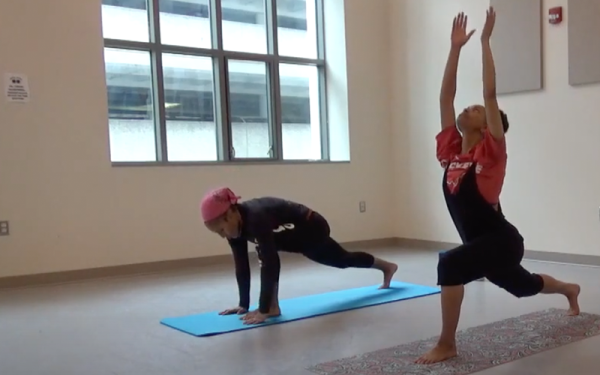 Two women practicing yoga on mats in a dance studio