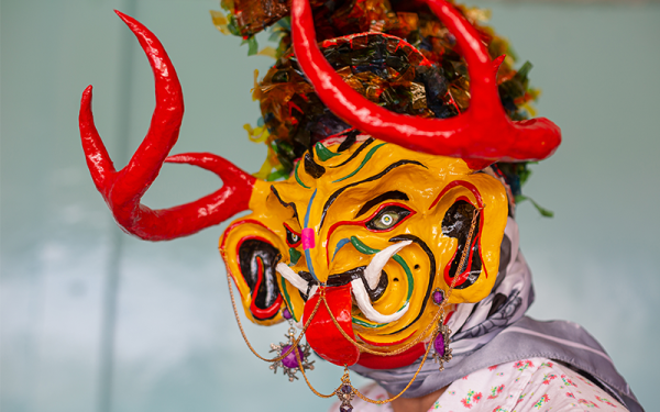 Person wearing brightly-colored devil mask
