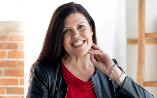 a smiling woman in a grey blazer and red shirt