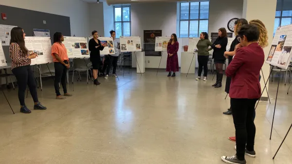 Graduate students standing by their research posters