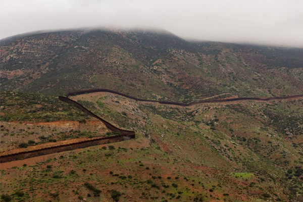 Photograph of border wall dividing mountainside