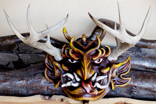 Carving of a masked face with antlers