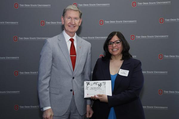 Two people posing with framed award