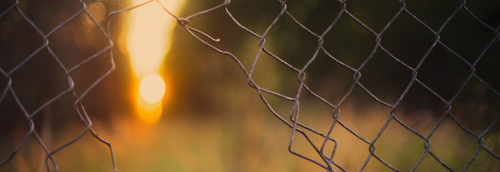 Photograph of chain link fence with hole in it