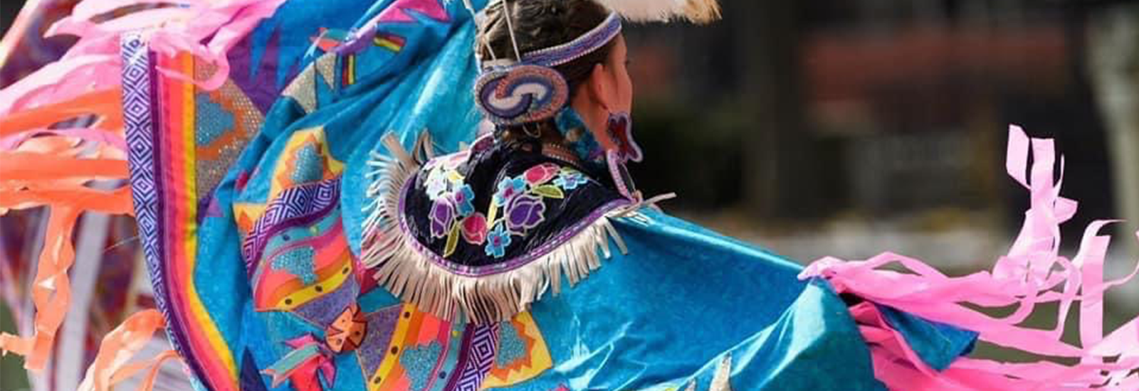 Person with a bright shawl dances at a Pow Wow