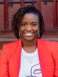 Smiling woman with short dark hair wearing a white shirt and red blazer